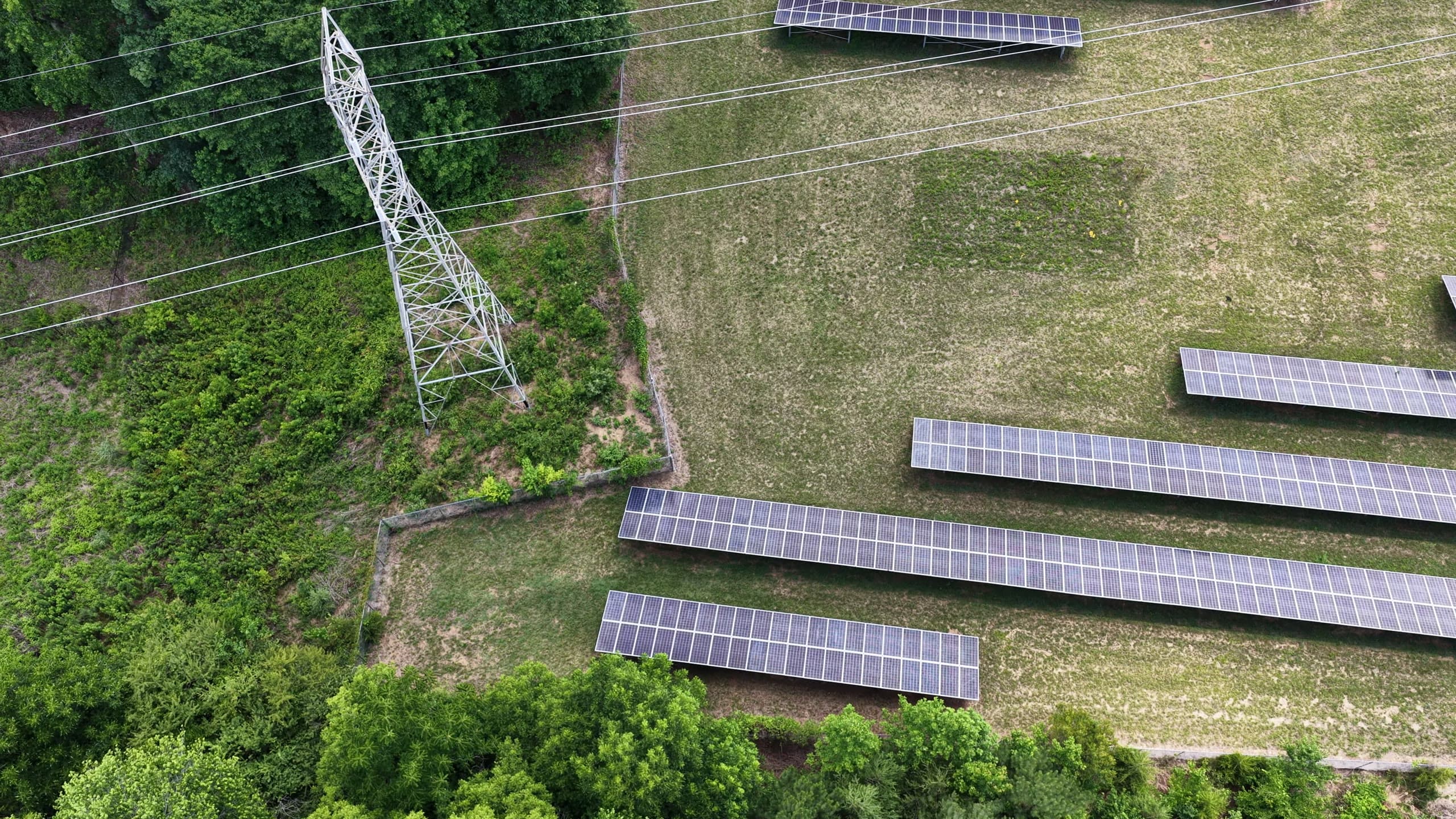 Steel lattice transmission tower recorded from a drone pass